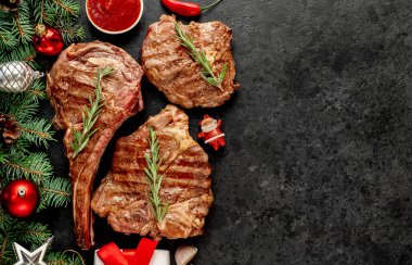 Biberiyeli ızgara biftek ve siyah arka planda baharatlar.