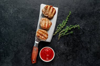 Soslu ızgara et ve siyah taşlı arka planda baharatlar. en üstteki görünüm.