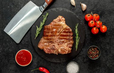 Biberiyeli ızgara biftek ve siyah arka planda baharatlar.