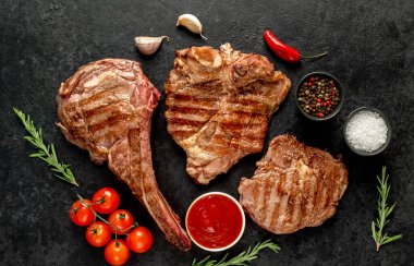 Baharatlı ızgara et ve siyah arka planda sebze.