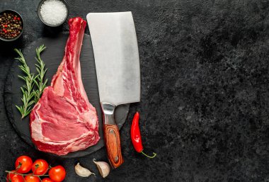 Baharatlı çiğ et ve siyah arka planda bitkiler