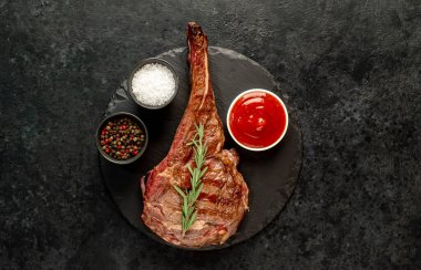 Baharatlı ızgara biftek ve siyah arka planda otlar.