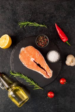 Baharatlı çiğ somon filetosu ve siyah taş kaplama otlar. en üstteki görünüm.