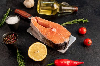 Baharatlı çiğ somon filetosu ve siyah taş arka planda otlar.