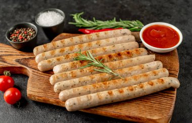 Biberiyeli ızgara sosis ve ahşap tahtada otlar.