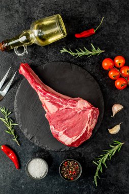 Baharatlı çiğ et ve siyah arka planda bitkiler