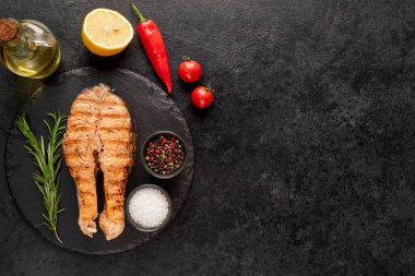 Sebzeli çiğ somon bifteği ve siyah taş arka planda baharatlar. Üst Manzara. Boşluğu kopyala.