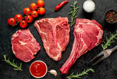 Biberiyeli çiğ biftek ve siyah arka planda otlar.