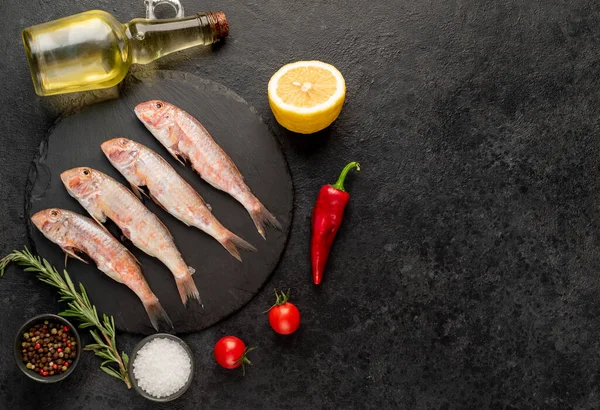 Baharatlı çiğ balık ve siyah taş arka planda bitkiler. en üstteki görünüm.