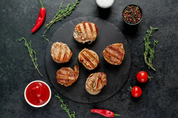 Biberiyeli ızgara et pirzolası ve siyah taş kaplama otlar. en üstteki görünüm.