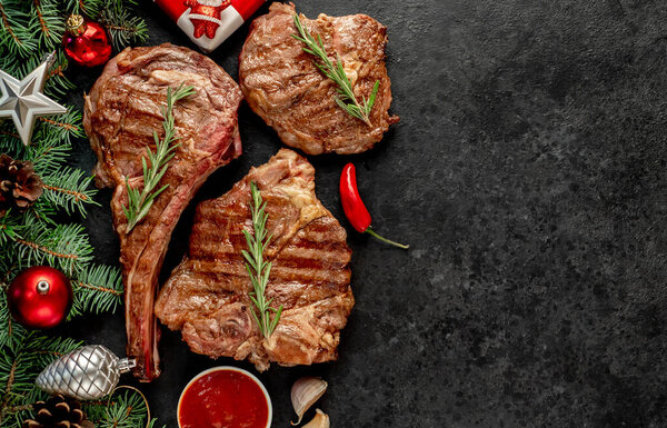 Grilled beef steak with vegetables and spices on black background