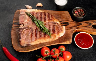 Biberiyeli ızgara biftek ve siyah arka planda baharatlar.