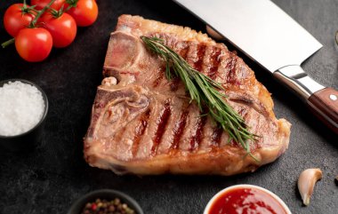 Biberiyeli ızgara biftek ve siyah arka planda baharatlar.