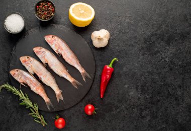 Siyah arka planda baharatlı çiğ balık