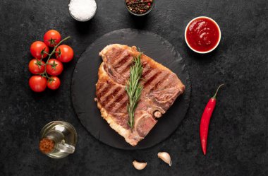 Biberiyeli ızgara biftek ve siyah arka planda baharatlar.