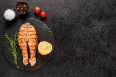 Siyah arka planda baharatlı ızgara somon bifteği.