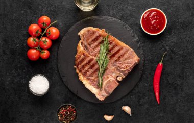 Biberiyeli ızgara biftek ve siyah arka planda baharatlar.