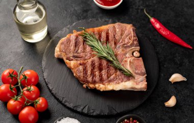 Biberiyeli ızgara biftek ve siyah arka planda baharatlar.