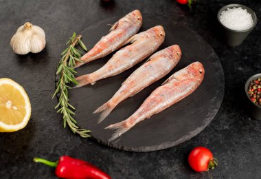 Siyah arka planda baharatlı çiğ balık