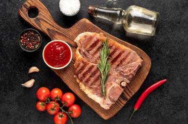 Biberiyeli ızgara biftek ve siyah arka planda baharatlar.