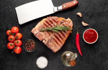 Biberiyeli ızgara biftek ve siyah arka planda baharatlar.