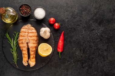 Siyah arka planda baharatlı ızgara somon bifteği.