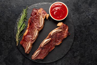 Baharatlı ızgara et ve siyah arka planda otlar.