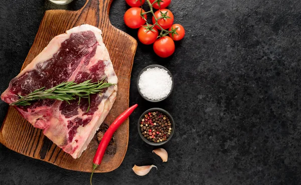 Bife Carne Crua Bone Com Especiarias Ervas Sobre Fundo Preto — Fotografia de Stock