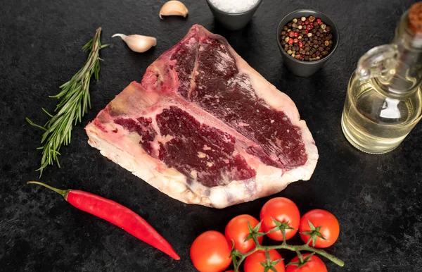 Rauwe Rund Bone Steak Met Specerijen Kruiden Zwarte Achtergrond — Stockfoto
