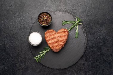 Biberiyeli ızgara biftek ve siyah arka planda baharatlar. en üstteki görünüm.