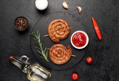grilled sausages with rosemary and spices on a black background. top view.