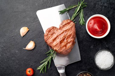 raw pork steak with spices and rosemary on black stone background. top view.