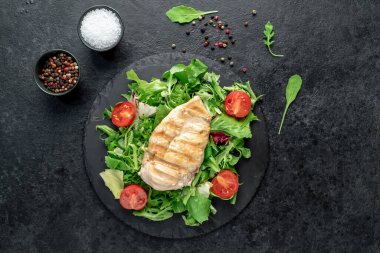 grilled chicken breast with vegetables  on a black plate. top view. 