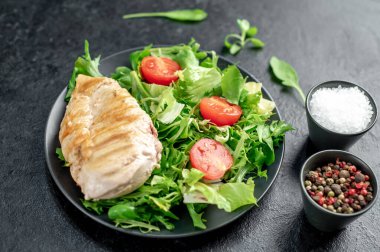 grilled chicken breast with vegetables  on a black plate. top view. 