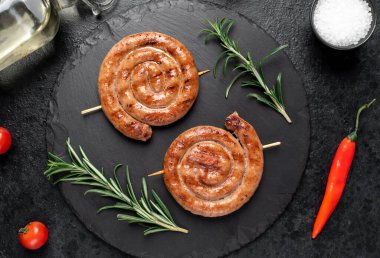 grilled sausages with rosemary and spices on a black background. top view.