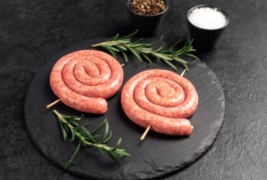 raw meat  sausages with rosemary and spices on a black background. top view.