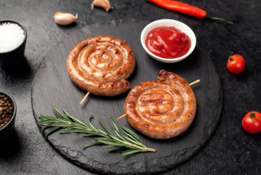 grilled sausages with rosemary and spices on a black background. top view.
