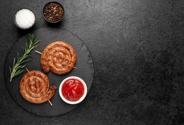 grilled sausages with rosemary and spices on a black background. top view.