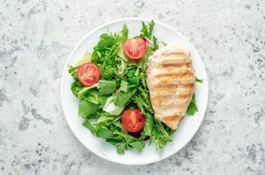 grilled chicken breast with vegetables  on a black plate. top view. 
