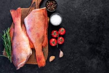 Siyah masada biberiye ile süslenmiş kırmızı çiğ balıklar. 