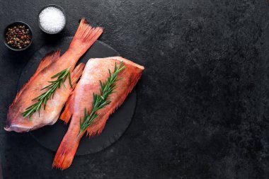 Siyah masada biberiye ile süslenmiş kırmızı çiğ balıklar. 