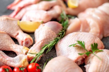 Siyah arka planda bulunan çeşitli çiğ tavuk parçaları.