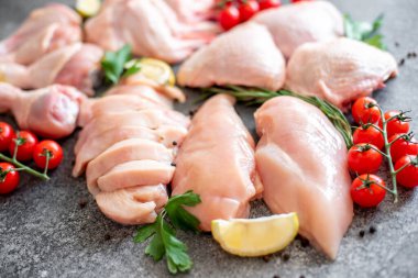 Siyah arka planda bulunan çeşitli çiğ tavuk parçaları.