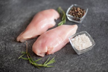 Çiğ tavuk filetosu, şifalı otlar ve yemek malzemeleri.