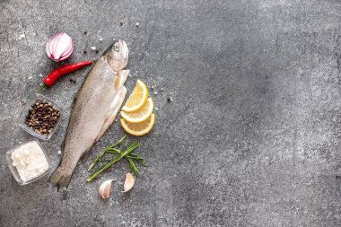 Koyu arkaplanda malzemeli çiğ alabalık.