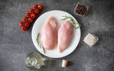 Çiğ tavuk filetosu, şifalı otlar ve yemek malzemeleri.