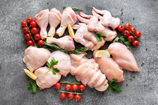 Assorted raw chicken parts with ingredients on black background