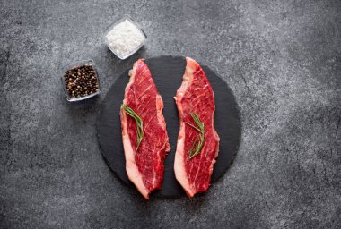 Siyah taşlı arka planda baharatlı ve otlu çiğ biftek.