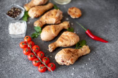 Baharatlı tavuk budu ve siyah taş arka planda otlar.