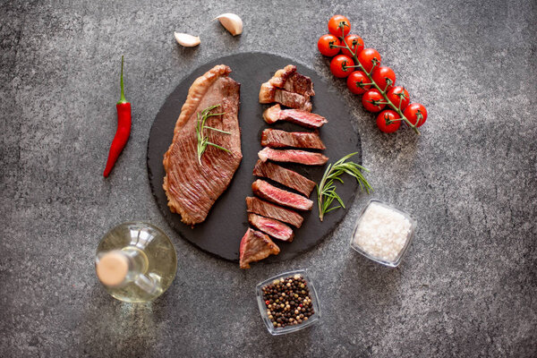 grilled beef steak with vegetables and spices on black background